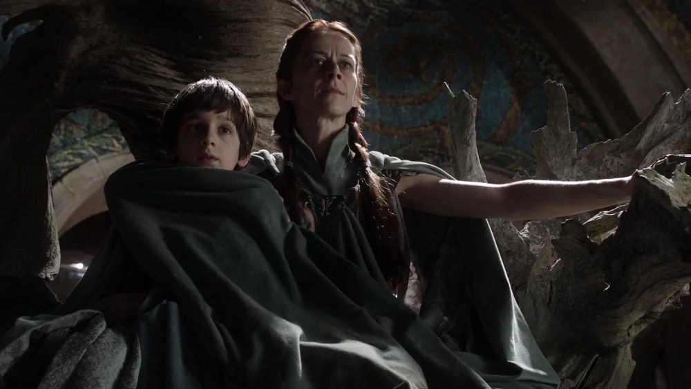 Lysa Arryn impose sa présence dans le Val, aux côtés de son fils Robin Lysa Arryn et son fils Robin assis sur le trône du Val dans Game of Thrones, scène emblématique du pouvoir familial