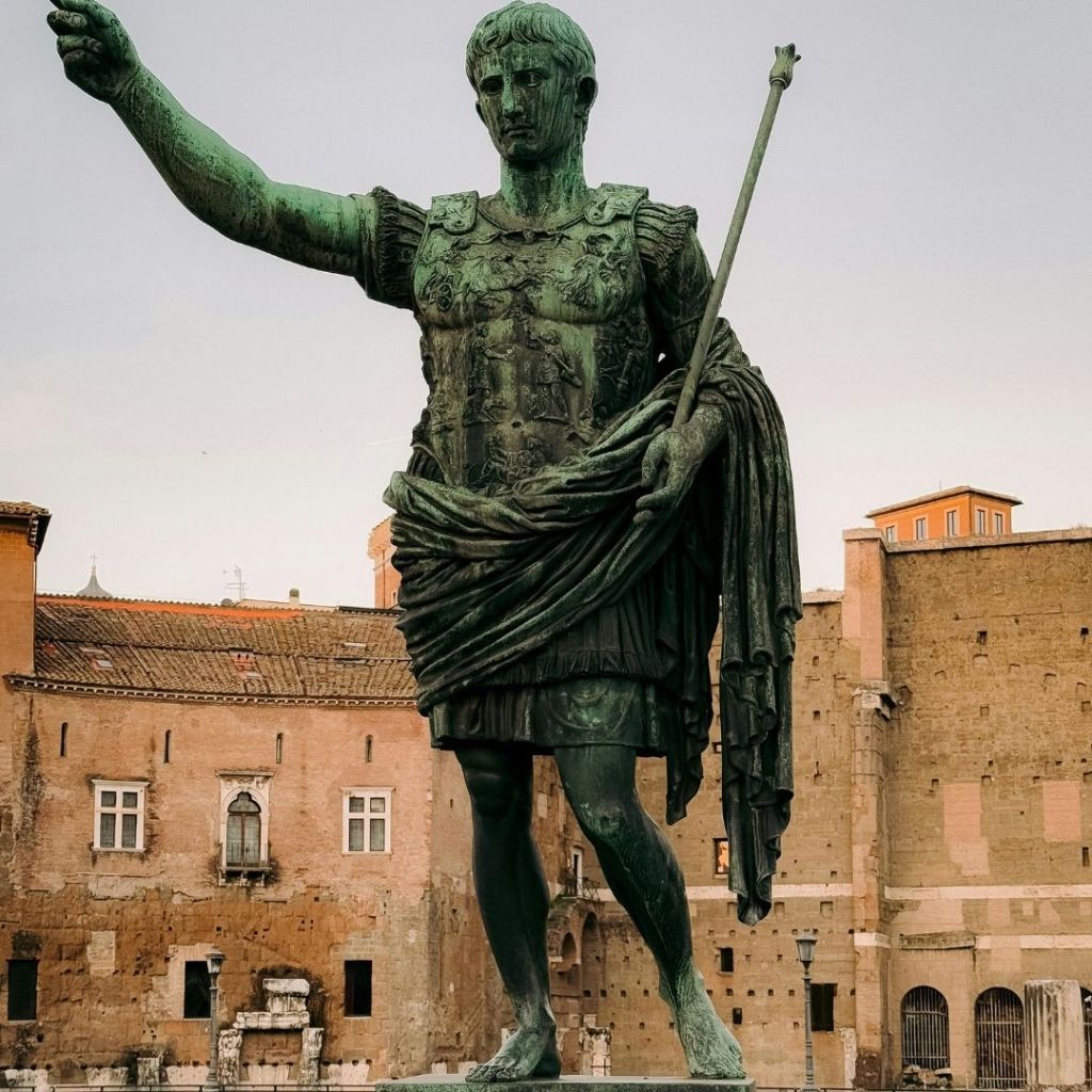 Statue en bronze de l’empereur Auguste en tenue militaire romaine, le bras levé.
