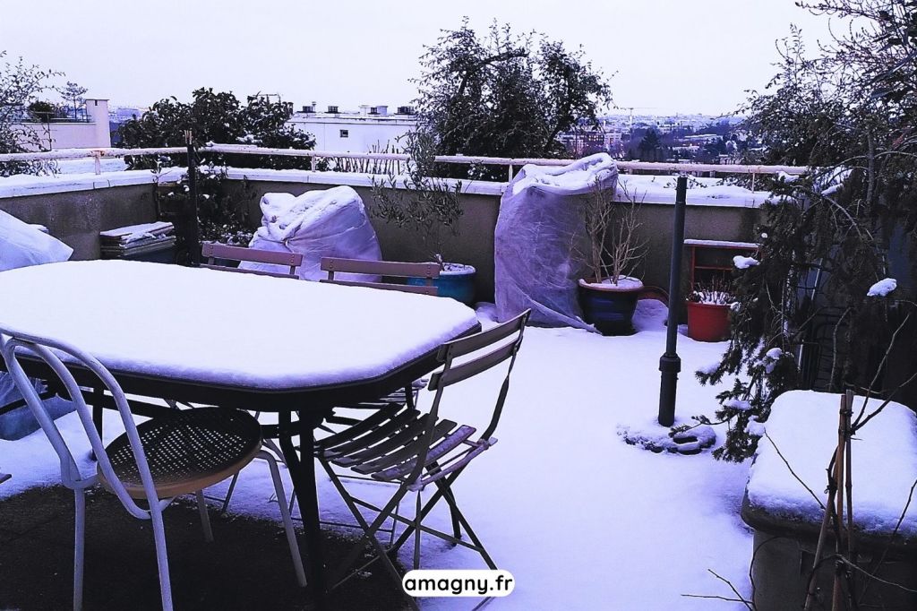 Terrasse enneigée avec table et chaises en hiver dans un cadre urbain