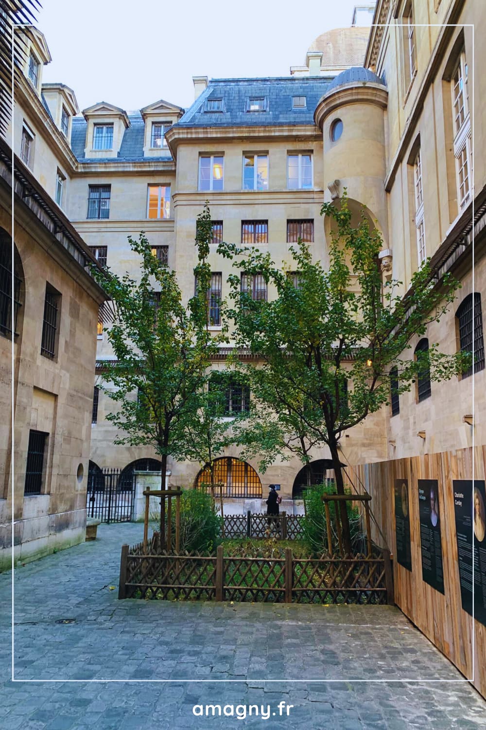 Cour intérieure de la Conciergerie de Paris avec arbres et panneaux d’exposition.