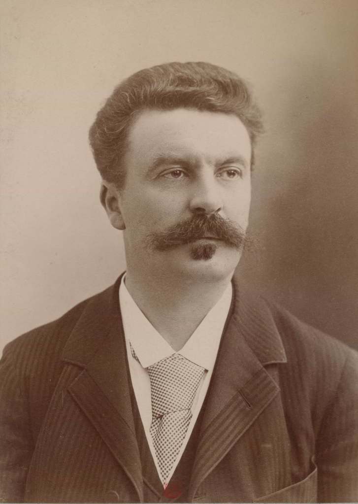 Portrait studio de Guy de Maupassant, moustache imposante et costume trois pièces.