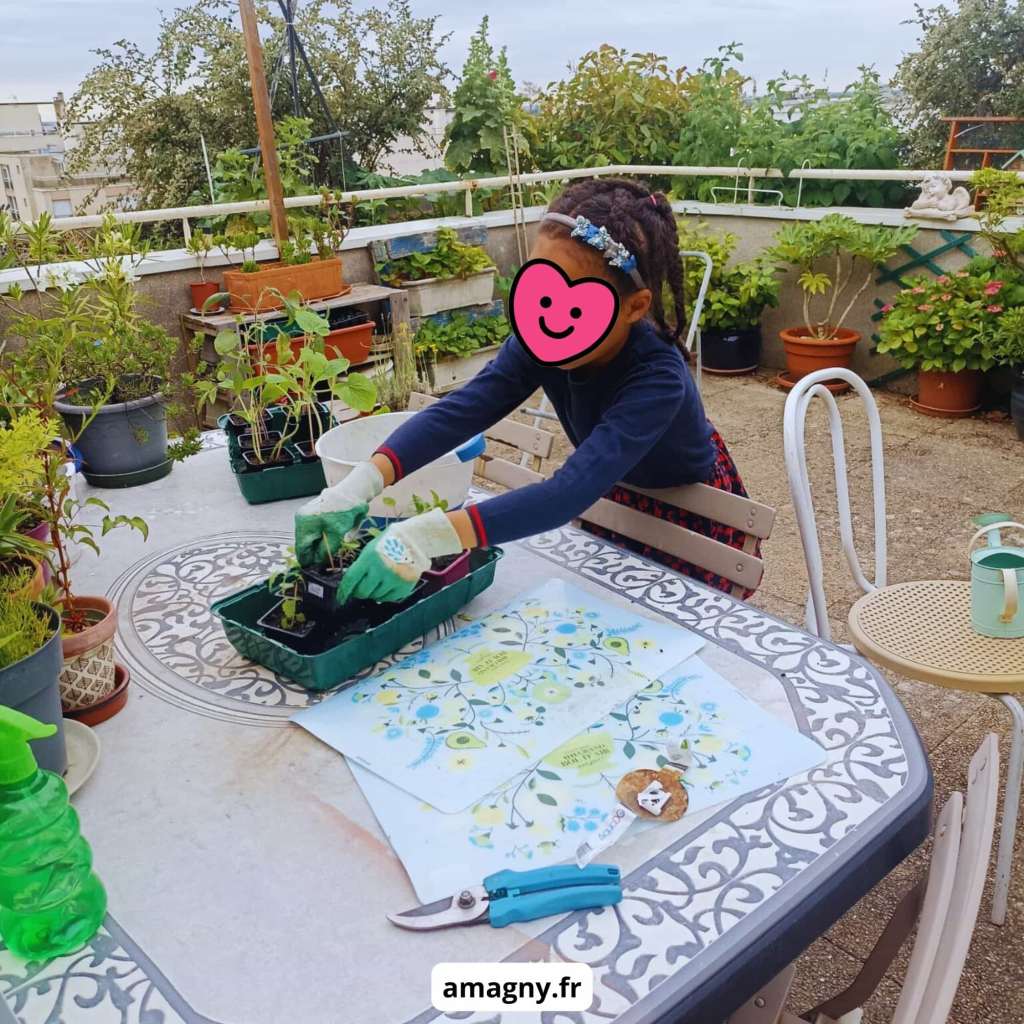 Enfant jardinant sur un toit-terrasse, manipulant des semis sur une table entourée d’outils.