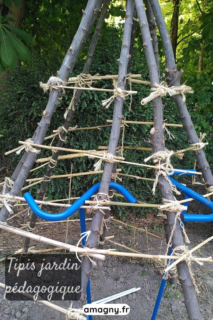 Structure de tipi en branches et bambous installée dans un jardin pédagogique.