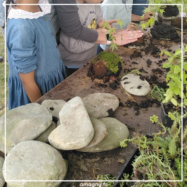Enfants réalisant un Ishitsuki en disposant terre, mousse et petites plantes sur des pierres.