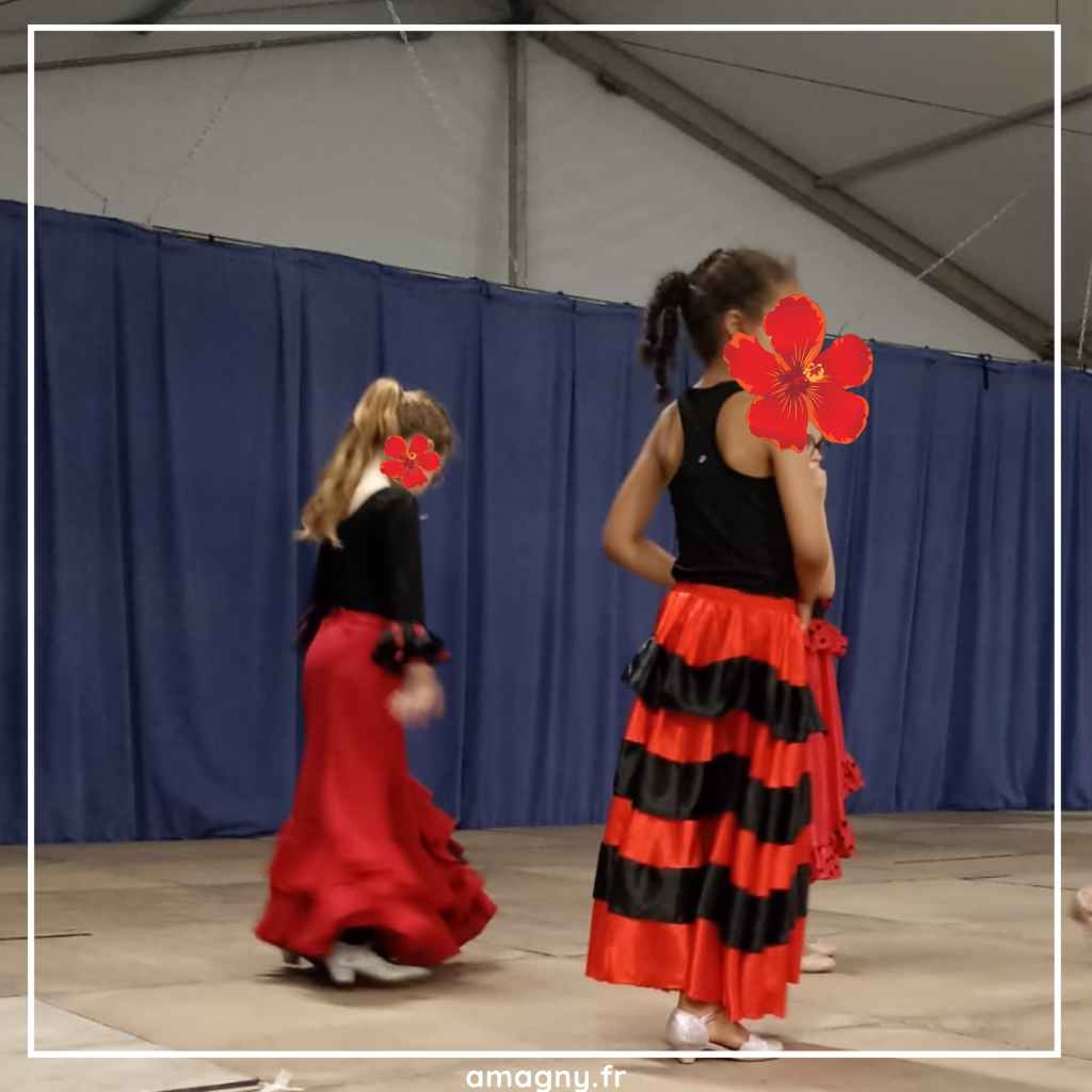 Groupe de jeunes danseuses en costumes rouges et noirs se produisant sur scène.
