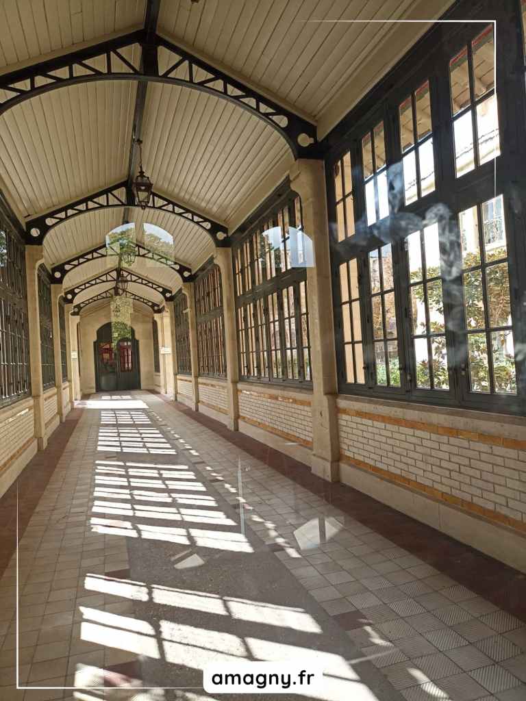 Couloir lumineux avec voĂ»te mĂ©tallique, grandes fenĂȘtres et jeux dâombres gĂ©omĂ©triques.