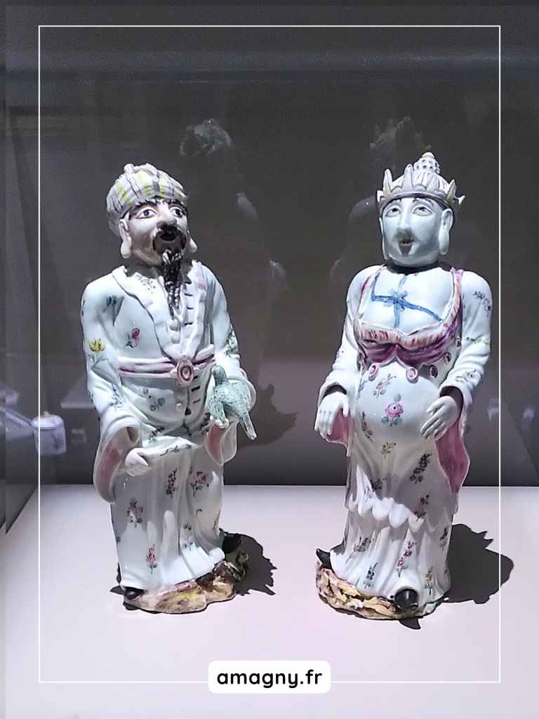 Figurines en porcelaine représentant un homme en turban tenant un animal et une femme couronnée en robe fleurie, exposées au château de Sceaux.