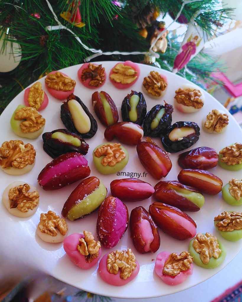 Assortiment de dattes farcies à la pâte d’amande colorée et disques décorés de noix. 