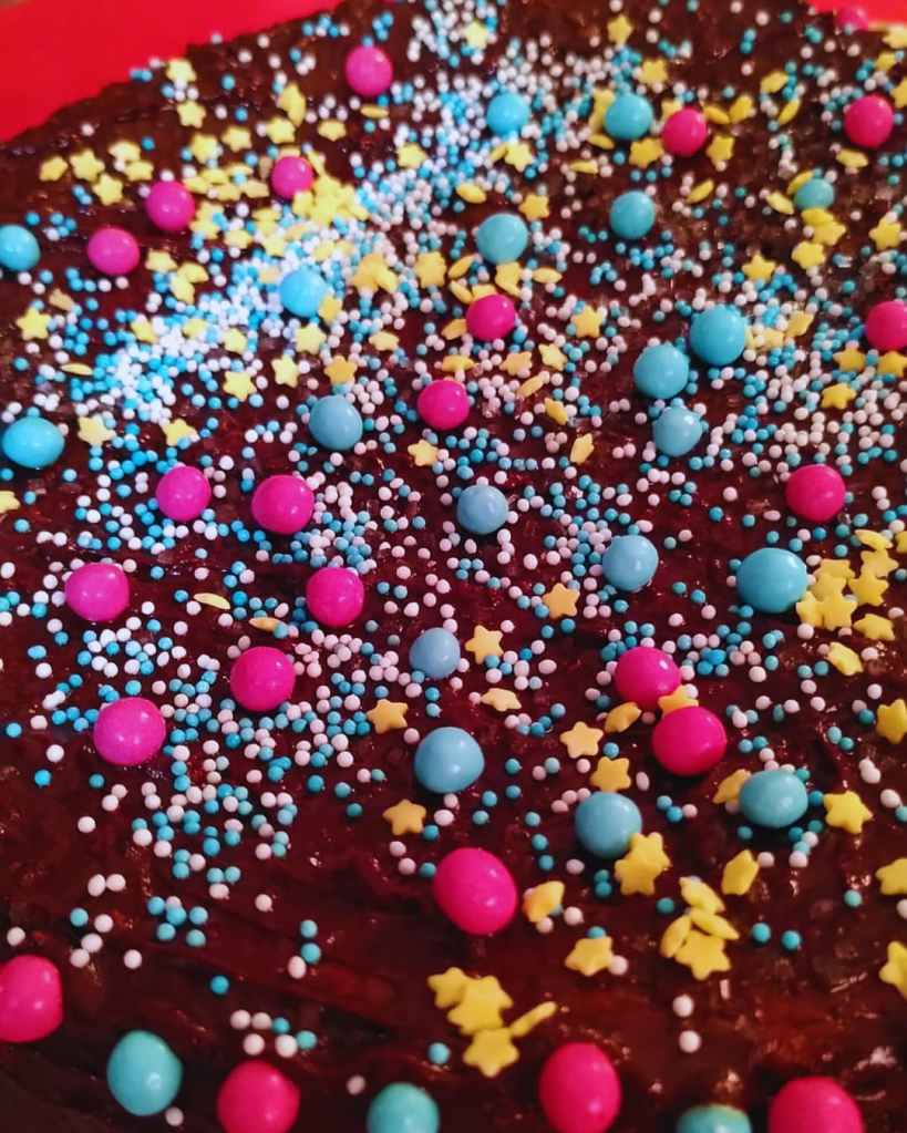 Surface de gâteau aux marrons nappée de chocolat et décorée de vermicelles et étoiles colorées. 