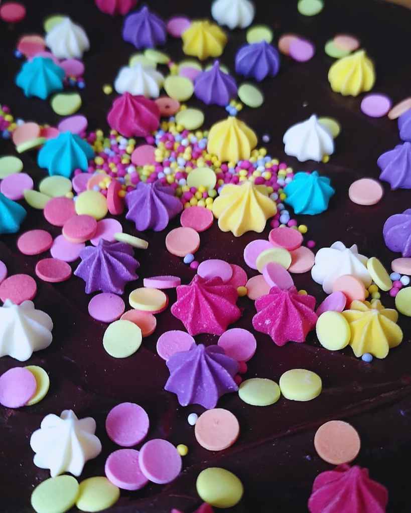 Surface de moelleux au chocolat décorée de vermicelles, confettis et étoiles colorées. 