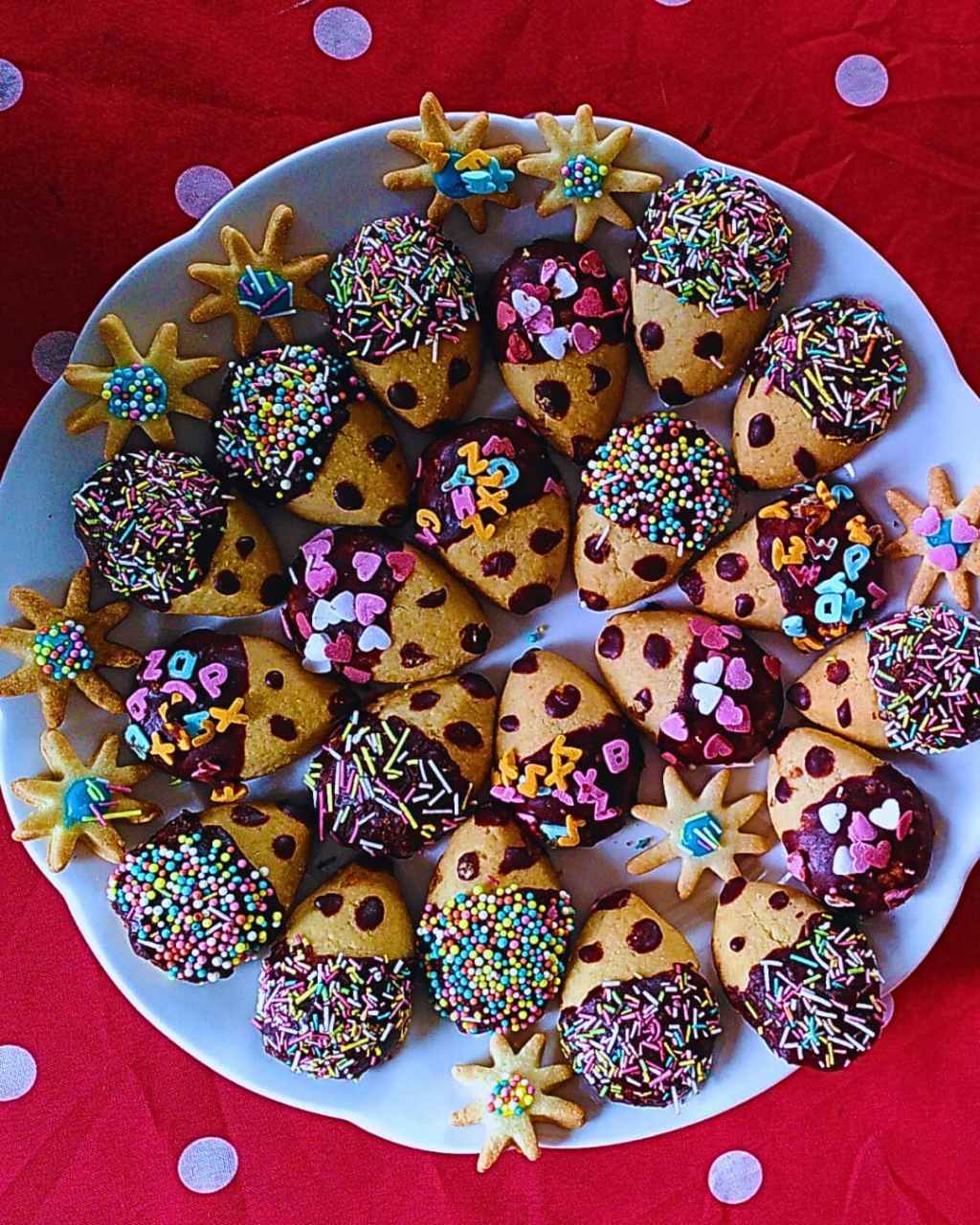 Biscuits en forme de hérisson décorés de chocolat et de vermicelles colorés sur assiette blanche.