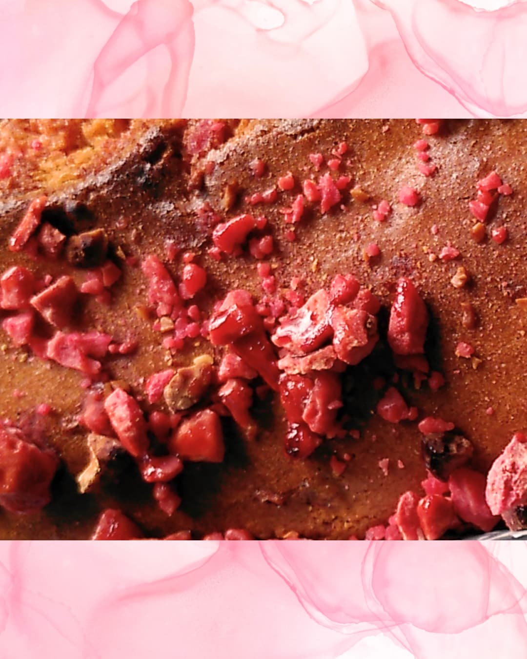 Cake doré garni de pralines roses concassées sur planche en bois.