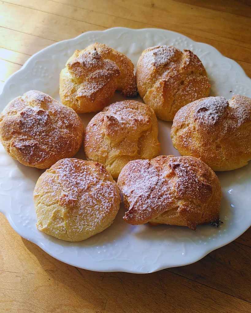 Choux dorés saupoudrés de sucre glace, présentés sur une assiette blanche.