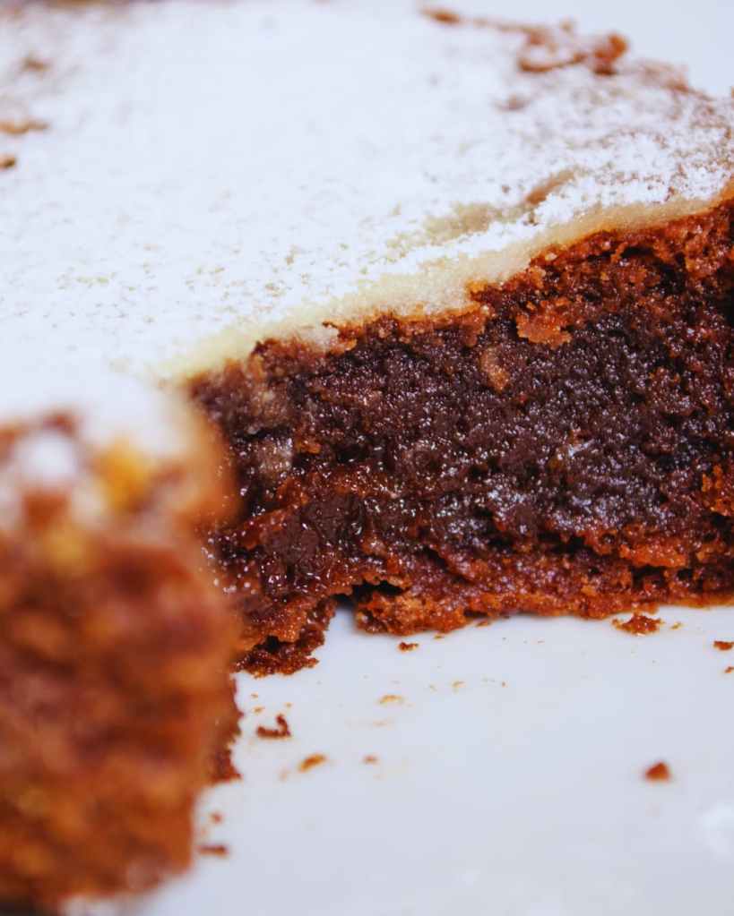 Part de gâteau au chocolat saupoudrée de sucre glace sur fond sombre.