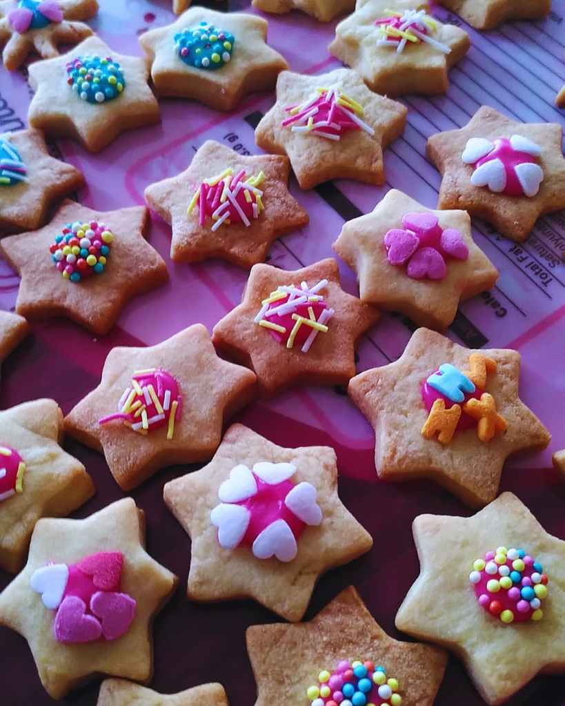 Biscuits en forme d’étoile décorés de cœurs, perles et vermicelles colorés.