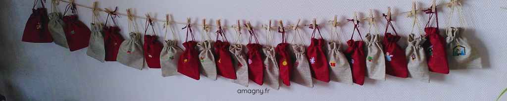 Calendrier de l’Avent artisanal avec 24 sachets brodés suspendus, rouges et beiges, décorés de motifs de Noël.