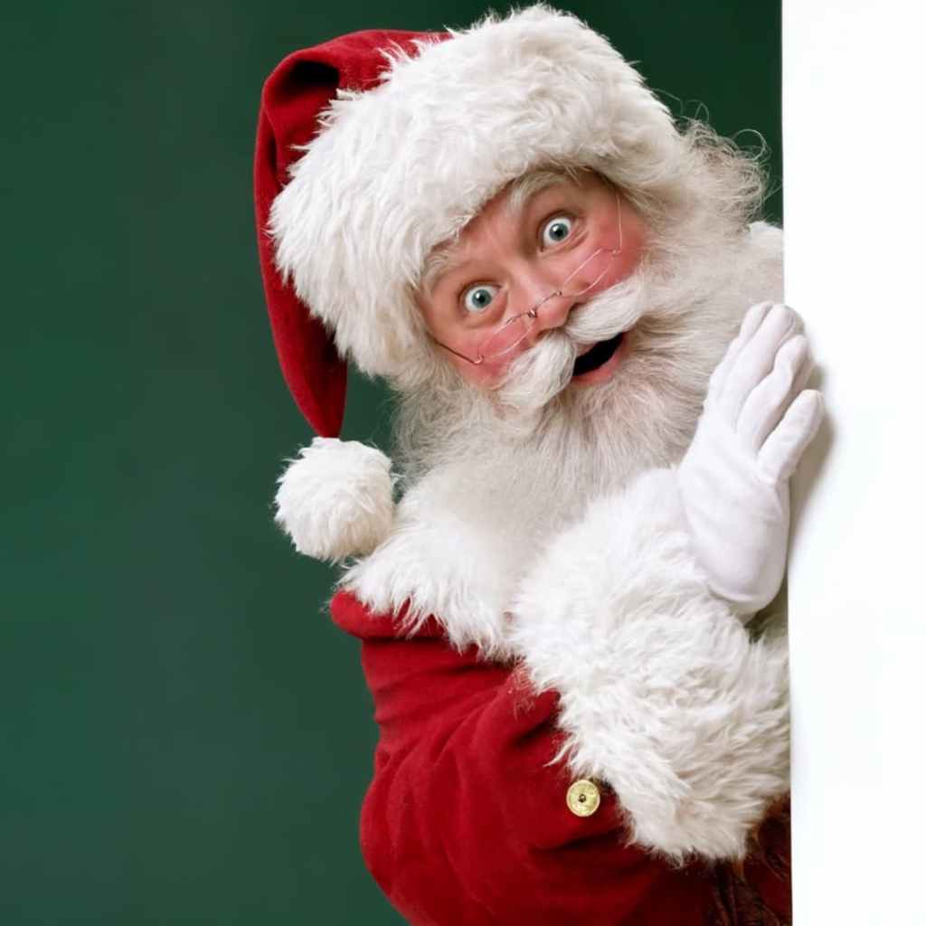 Père Noël en tenue rouge et lunettes rondes, apparaissant derrière une surface blanche sur fond vert.