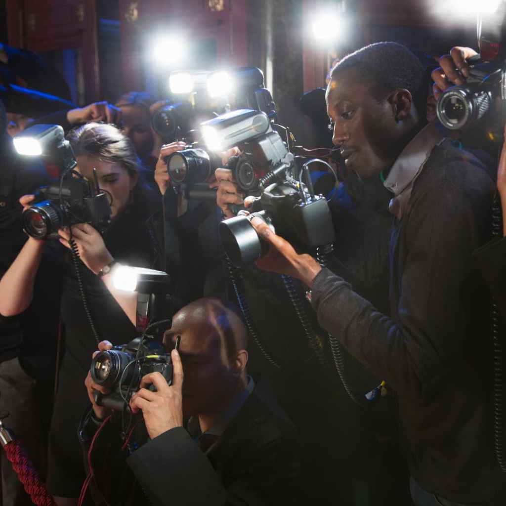 Groupe de photographes professionnels utilisant des appareils photo avec flash lors d’un événement médiatique.